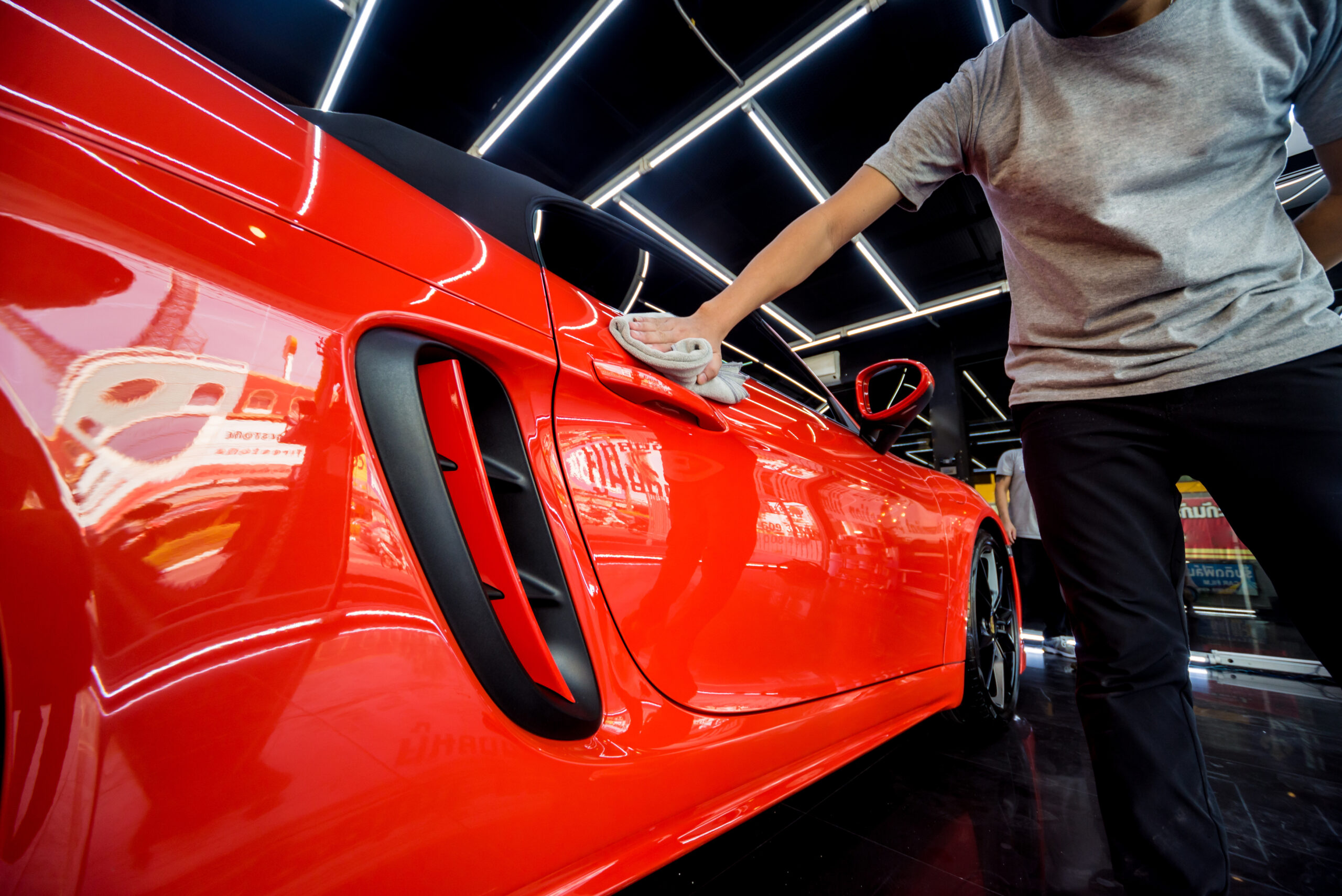 a technician applying ceramic coating to a red sports car at G-Force Films